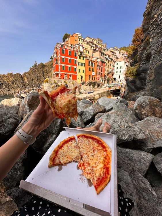 eating pizza on the rocks in Riomaggiore, how to travel cheap