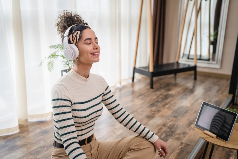 a woman is sitting on the floor with headphones and making time for herself
